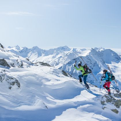 Drei Bergsteiger bei einer Skitour beim Hinaufklettern auf einem Grat