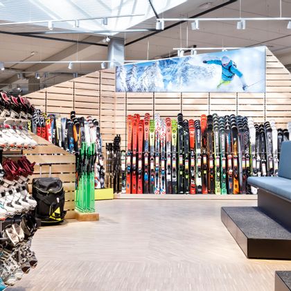 Skischuhe und Sitzbänke im Vordergrund, Skiwand im Hintergrund