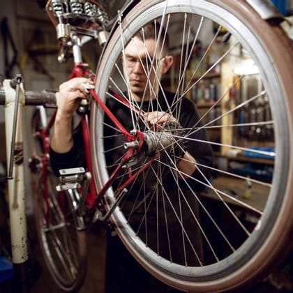 ein Rad ist in einer Werkstatt aufgehängt, während ein Mechaniker daran arbeitet