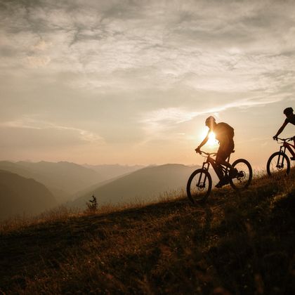 Radfahrer fahren den Berg runter bei einem Sonnenuntergang