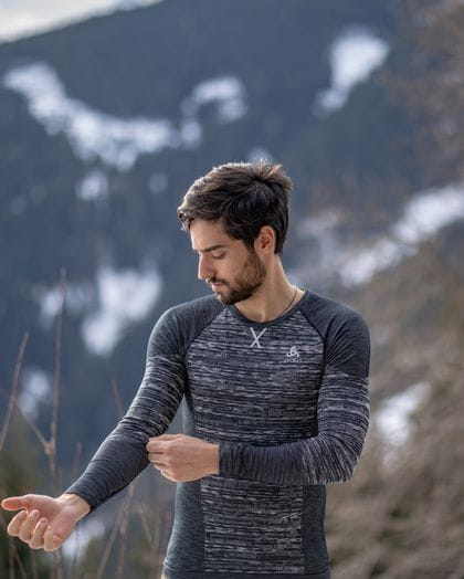 Young man with black hairs wearing a gray ski baselayer from Odlo