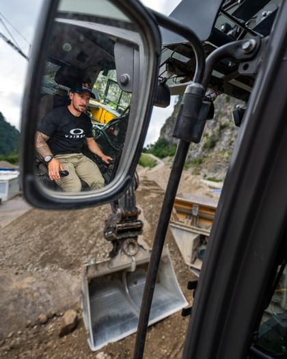  Marcel Hirscher sitzt konzentriert im Führerhaus eines Baggers und bedient die Maschine.