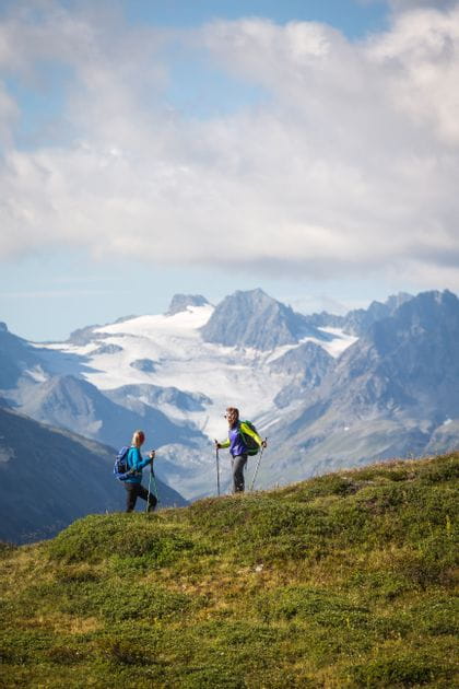 two hikers in front of summer alps with snow-covered mountain tops