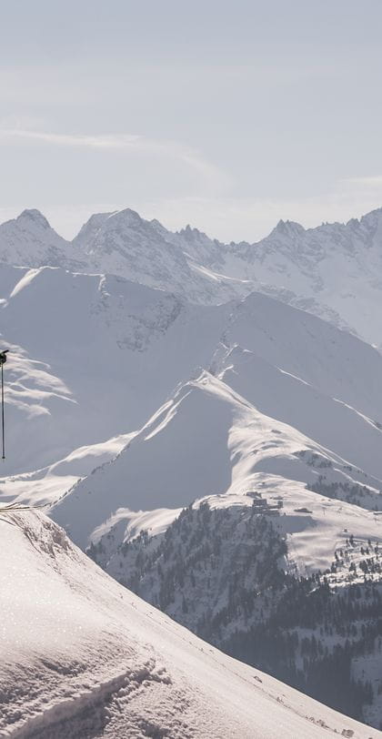 zwei Skifahrer stehen auf einem Vorsprung und blicken in die Ferne
